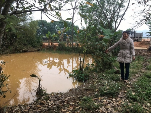 Bà Nguyễn Thị Sen chỉ tay về ao cá nhà mình bị ô nhiễm do khai thác đất gây ra